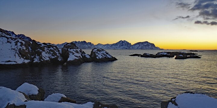 Impressive winter landscape with snow-covered mountains and rocks in a calm sea at sunset, Winter, Nyksund, Langoya, Vesteralen, Nordland, Norway