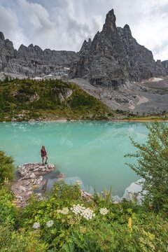 Young woman, hiker at the turquoise-green Sorapis lake, Lago di Sorapis, mountain peak Dito di Dio, Dolomites, Belluno, Italy