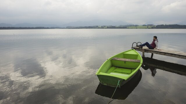 Woman 50+, wooden jetty, green rowing boat, Hopfensee, Hopfen am See, near F&uuml;ssen, Ostallg&auml;u, Allg&auml;u, Bavaria, Germany