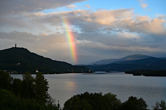 Bright partial rainbow over Lake Worthersee near Klagenfurt, Austria at sunrise.