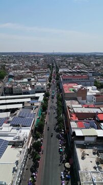 Aerial drone flight over a city avenue and rooftops with solar panels in downtown Aguascalientes on a sunny day, central Mexico.
