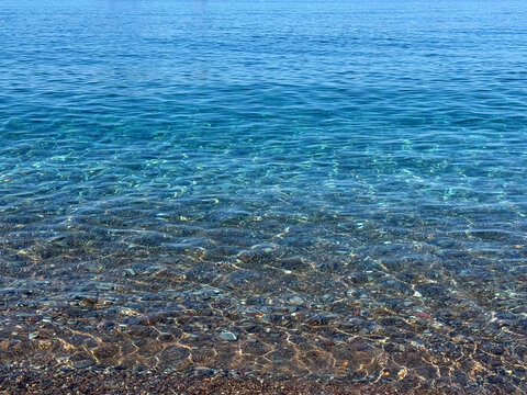 Blue sea clear water on pebble beach.