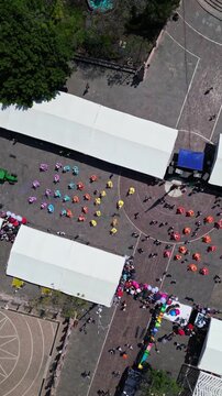Aerial drone view of parade contingents in the plaza with fair tents during the Feria de San Marcos in Aguascalientes, Mexico.