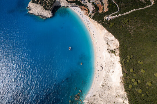Aerial view of Porto Katsiki beach with turquoise waters, white cliffs, and a small boat anchored in the Ionian Sea, Lefkada, Greece.