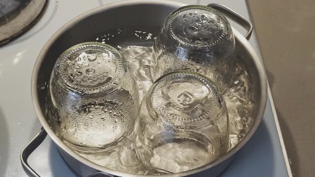 Top down view of empty glass jars being sterilized in boiling water. Preparation for making homemade jam, jelly, or pickled vegetables