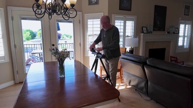 Senior film maker taking down a motion camera slider after creating content
