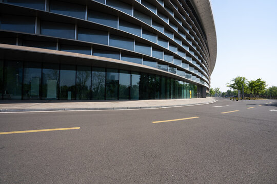 Curved glass facade modern building street view with asphalt road and yellow markings