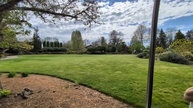 Scenic trolley ride past a paved walking path bordered by lush green grass and mature trees on a beautiful spring day, showcasing the peaceful landscapes and relaxing atmosphere.