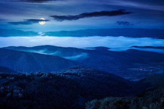 carpathian mountain landscape on a foggy night. outdoor adventure with stunning view. full moon over mountainous countryside of ukraine in summer. mysterious rolling hills