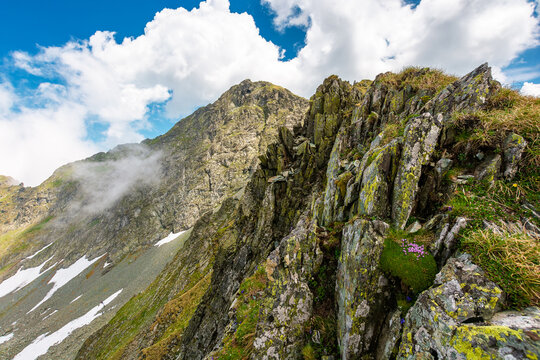 mountain landscape with steep rocky slopes. romania travel background. clouds on a blue sky above fagaras mountain ridge. stunning weather in summer