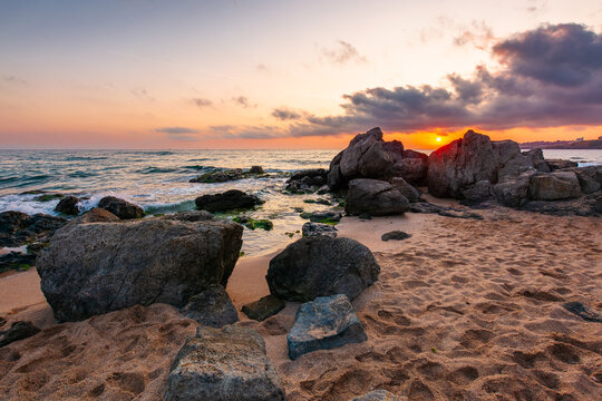 huge stones on a sandy beach at sunrise. wonderful summer vacation season at the black sea. calm waves washing the sand shore. nature background with cloudy sky. bulgaria travel photo