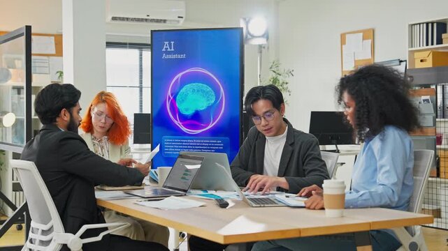 Diverse multiracial team planning new business strategy with AI marketing consultant on multiple screens and documents in modern open office, corporate restructuring and transformation concept