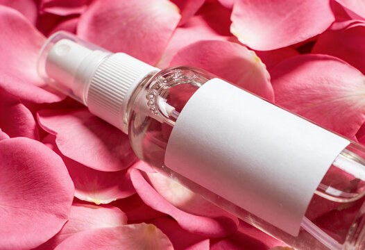 Rose Water Spray Bottle Mockup with Blank White Label on Pink Rose Petals Background for Beauty Branding.