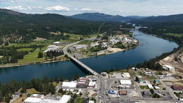 Aerial of highway bridge across Pend Oreille River in small town Newport Washington in summer with forested mountain backdrop