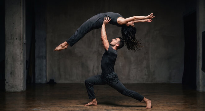 Professional dancers performing dramatic lift stunt in dark studio