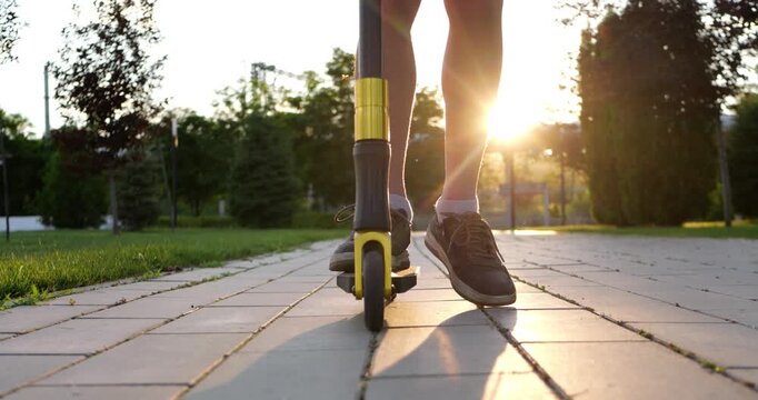 Boy places foot on skateboard in park during sunset, preparing for ride with anticipation and excitement. Low angle view captures courage, confidence and active childhood.