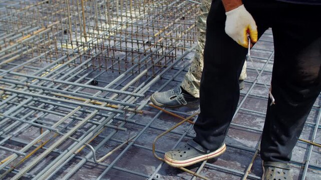 Workers tying steel reinforcement for concrete foundation