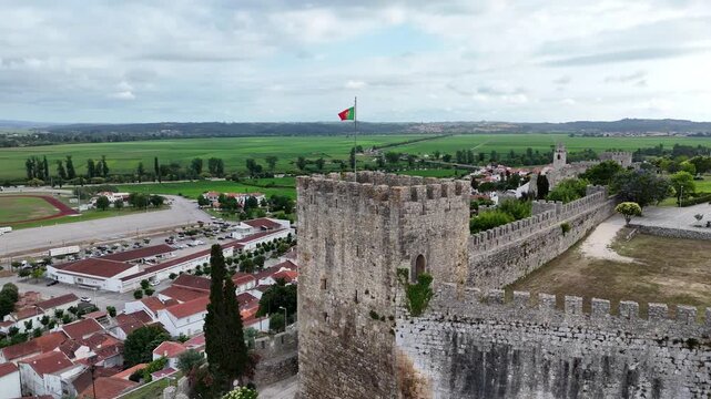 Drone orbit around the main tower of Montemor-o-Velho Castle with Portuguese flag