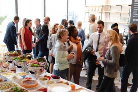Diverse group of people networking at a buffet-style event.