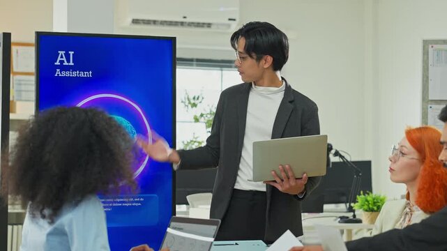 Smart Asian businessman presenting AI backend system replacing human marketing data management to partners and programmers in modern open office, business restructuring and automation concept