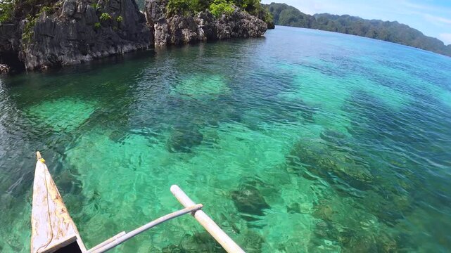 slow motion of horizontal pane view from right to left look out to shallow blue green turquoise peaceful lagoon from a small boat to coral rocks at Siete Pecados Marine Park Coron Philippines