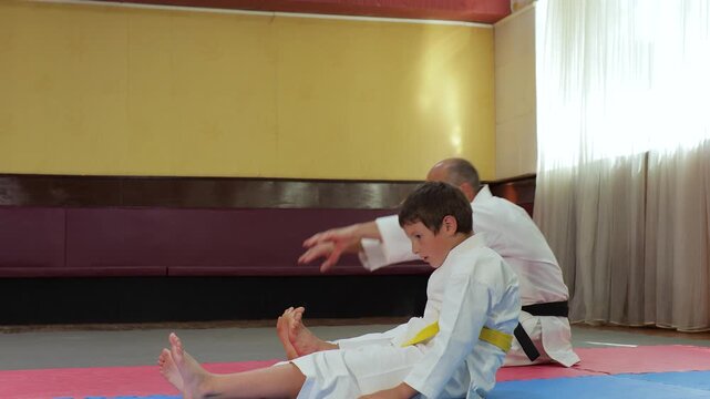 The trainer and the little athlete perform bends to straight legs