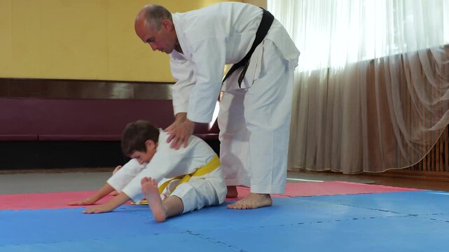Trainer helps little athlete perform stretching exercise