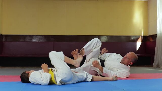 A trainer and a young athlete perform a side kick while lying down