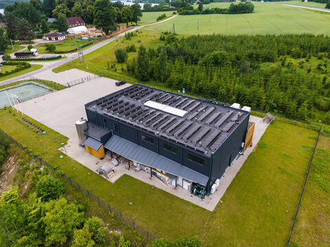 Ikskile, Ogre Municipality, Latvia - 24 June 2026: Aerial view of a modern cheese factory with solar panels on the roof, set amidst green fields and trees in a rural landscape.