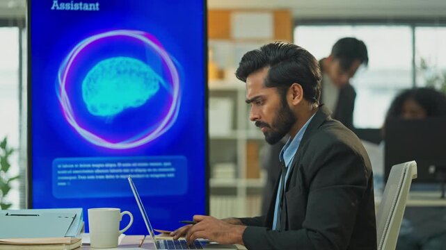 Indian male marketer using laptop and AI consultant on multiple screens to restructure business and marketing strategy in modern open office, South Asian professional digital transformation concept