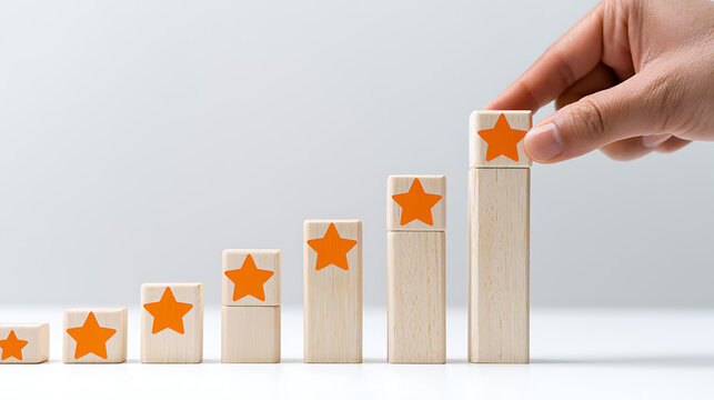Human hand places a wooden block with an orange star on a stack, forming a rising bar chart, symbolizing growth, achievement, and positive feedback