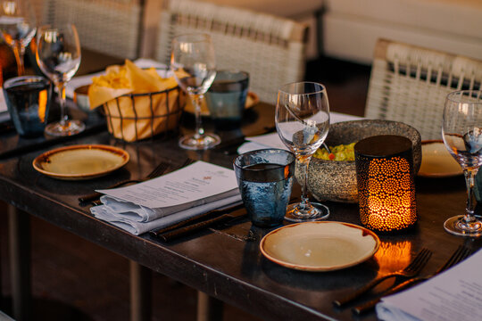 Elegant restaurant table setting with wine glasses, candle, stone bowl, tableware, and warm ambient lighting prepared for private dining experience