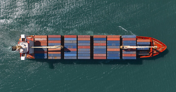 Spain - 25 June 2026: Aerial view of a large container ship navigating the deep blue waters of the Mediterranean Sea, showing rows of colorful cargo containers on deck.