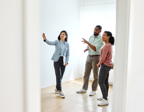 Female Real Estate Agent Selling And Showing The Modern Apartment To His Young Clients That Are Standing Next To Him In The Fancy Apartment