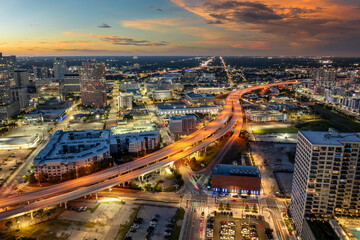 Fototapeta premium Contemporary nighttime city with elevated highway above downtown streets, moving cars and urban architecture in vibrant American metropolis.