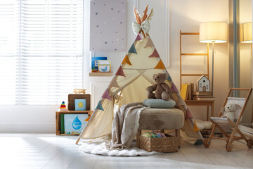 Beautiful wigwam, ottoman, different toys and books in child's room. Interior design © New Africa