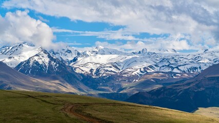 Fototapeta premium Dzhily-Su, Russia - June 4, 2026: View of the Caucasus Mountains along the road to Dzhily-Su, showing mountain peaks, valleys, winding road, open landscapes, and scenic natural surroundings.