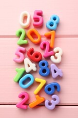 Fototapeta premium Many colorful numbers on pink wooden table, flat lay