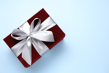 Fototapeta premium Beautiful velvet gift box on light blue background, top view. Space for text
