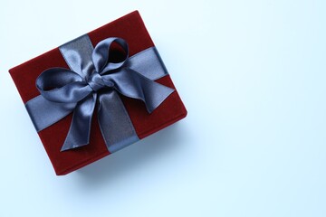 Fototapeta premium Beautiful velvet gift box on light blue background, top view. Space for text