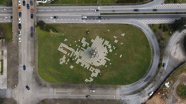 Maia, Portugal - 24 June 2026: Aerial view of Jardim das Piramides featuring a geometric stone pattern on a green lawn surrounded by urban roads and traffic.