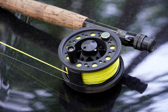 Fly-fishing reel and rod with bright fly line on black background