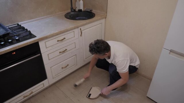 Man cleans kitchen. Person tidies up cozy space. Caucasian male performs sustainable cleaning in compact apartment kitchen, utilizes environmentally safe tools to tidy up small cozy apartment kitchen