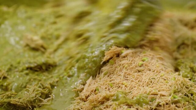 A decadent close-up shot showing the preparation of the trending Dubai chocolate bar filling. Vibrant green pistachio cream is being mixed with golden, crispy shredded kataifi dough to create a rich, 