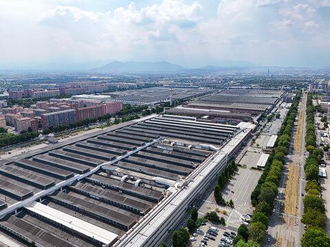 Torino, Italy - 24 June 2026: Aerial view of the Stellantis Battery Technology Center featuring large industrial factory buildings with sawtooth roofs surrounded by urban infrastructure and trees.