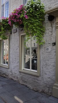 Charming view of a historic stone house facade adorned with vibrant hanging flower boxes on a street in Old Quebec City Canada