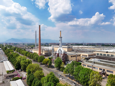 Torino, Italy - 24 June 2026: Aerial view of the Battery Technology Center STELLANTIS, featuring industrial facilities, tall chimneys, and surrounding trees under a blue sky.