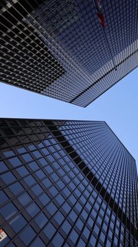 Looking up at the iconic dark glass office towers of the financial district against a clear blue sky in downtown Toronto Canada