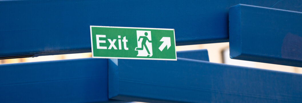 Illuminated emergency exit sign indicating evacuation route in buildings, symbolizing safety guidance, emergency preparedness, and directional information for occupants during hazardous situations.