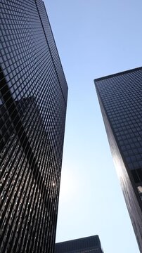 Looking up at the iconic dark glass office towers of the financial district against a clear blue sky in downtown Toronto Canada